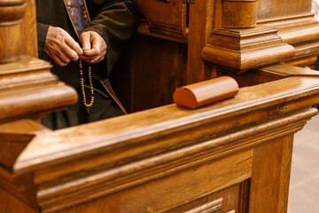 a confessional where a Catholic priest sits and confesses the faithful. Focus on the hands of the...