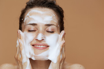 relaxed young woman with foaming face wash washing face
