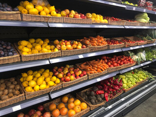 Various fresh vegetables and fruits on shelves in supermarket