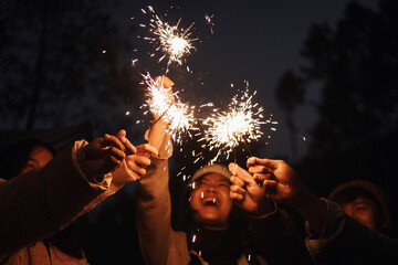 Happy young multiethnic friends enjoy playing a sparklers firework in a party