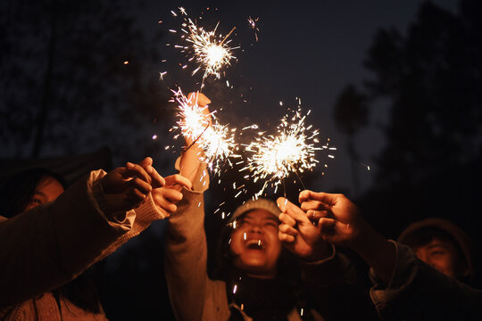 Happy young multiethnic friends enjoy playing a sparklers firework in a party - Powered by Adobe