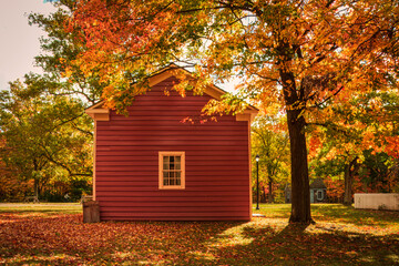 A small red house blends with the autumn foliage , canadian fall, canadian heritage village