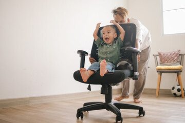 Happy father and son playing with swivel chair at home