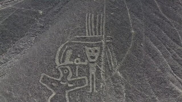 Close up view of single human figure and bird camera rising up to high POV of the Nazca Lines geoglyphs made in the soil of the Nazca Desert Aerial video