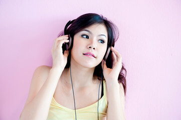 A young, attractive Asian woman is happily listening to music.