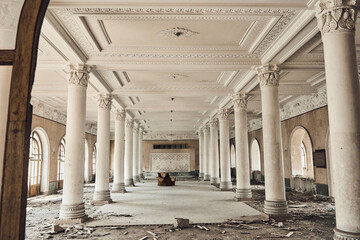 Abandoned soviet spa resort (sanatorium) Shakhter (Miner), in Tskaltubo, Georgia. View of the empty big hall with columns, an old chair in the center. 
 - obrazy, fototapety, plakaty