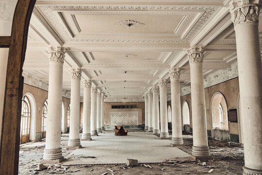 Abandoned soviet spa resort (sanatorium) Shakhter (Miner), in Tskaltubo, Georgia. View of the empty big hall with columns, an old chair in the center. 
