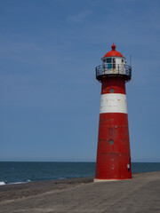 Westkapelle lighthouse, in the Netherlands. Red lighthouse with white stripe. Blue sky in the background.