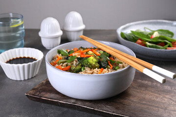 Tasty fried rice with vegetables served on grey table, closeup
