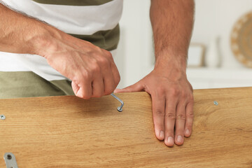 Man with hex key assembling furniture indoors, closeup