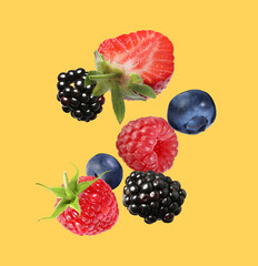 Many different fresh berries falling on golden background