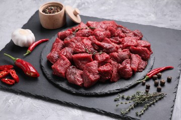 Pieces of raw beef meat, products and spices on grey textured table