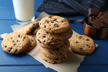 Tasty chocolate chip cookies and glass of milk on blue wooden table, closeup