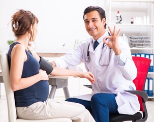 Young doctor checking pregnant woman's blood pressure