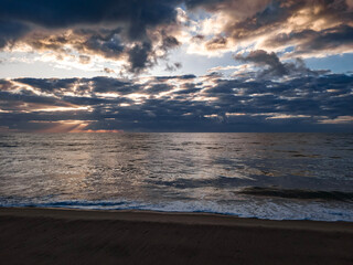 Sunrise over the sea, sunlight between the clouds, rays of light, sunrise on the beach
