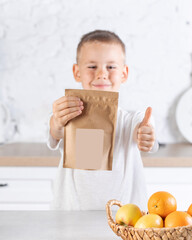 A cute boy stands and holds a craft package with a place for your logo and advertising. 