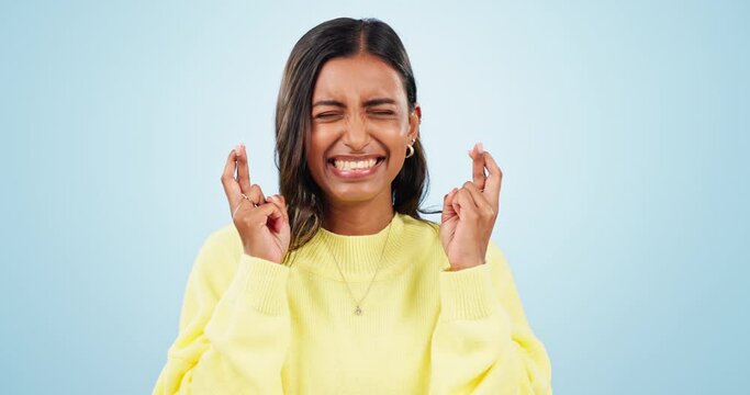 Wish, hope and fingers crossed with woman with good luck sign for success, winner and faith. Studio, blue background and female person with emoji, excited and optimism hand gesture with smile