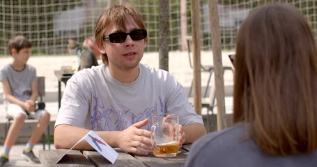 Casual Social Drinking. Guy on a date with a glass of beer. Drinking a glass of beer on a date may simply indicate that he enjoys alcohol casually and is comfortable having a drink in social setting. - Powered by Adobe