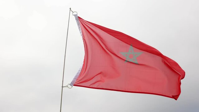 Flag of morocco flying proudly in wind with sky as background Moroccan flag flying beautifully in wind with gray sky behind country. High quality 4k footage