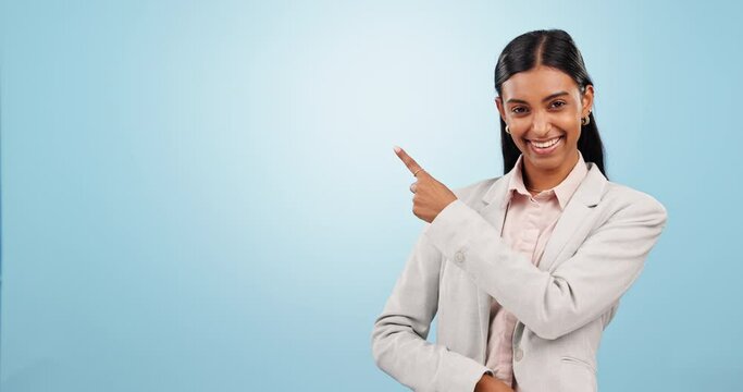 Face, business woman and pointing to advertising space, mockup and promotion in studio on blue background. Portrait, happy indian worker and presentation of announcement, news or information about us