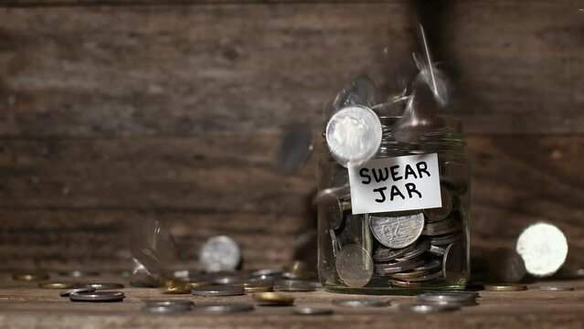 Medium, low, front on shot, Australian coins quickly falling into and around a glass Swear Jar,  rustic wooden setting, concept, copy space