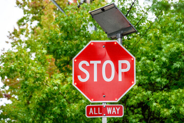 Stop sign with flashing LED lights powered by a solar panel, all way sign below
