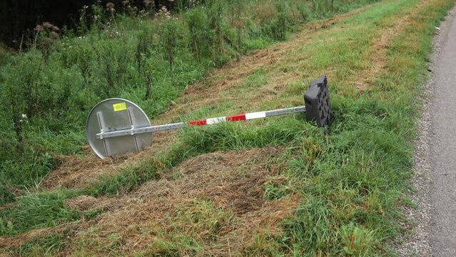 Backside of circular sign with red and white caution metal post on plastic base on side of road