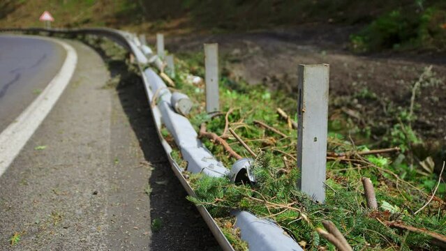 Guardrail ripped off of metal support beams on side of road from mudslide that tore trees off hill