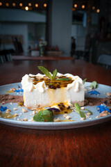 En una mesa  torta de maracuyá  con crema de leche y queso crema. 