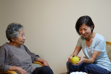 梨を剥きながらくつろいで談笑する高齢女性と中年女性