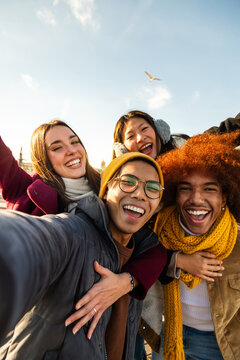 Selfie of multiracial happy friends enjoying winter day outdoors. Happy people looking at camera. Vertical. Copy space.