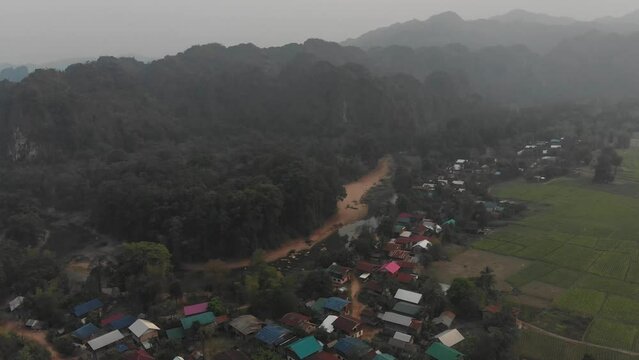 Drone view of small rural village near Kong lor cave on cloudy day, aerial