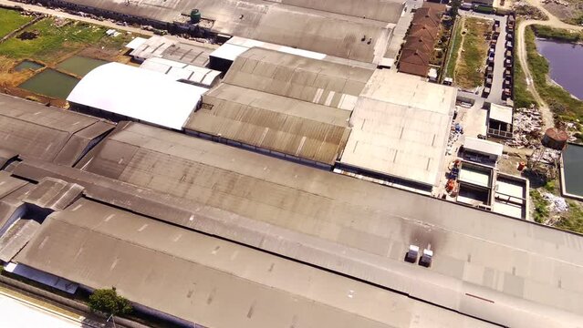 Top View Of Textile Factory. Aerial Drone Footage Of A Factory Containing Factory Buildings, Waste Storage, Warehouses And Heavy Equipment On The Edge Of Bandung City. Drones 4K Videos