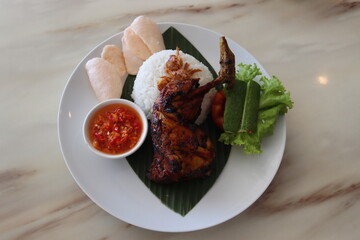 spicy chicken roasted with hot rice and raw vegetables,cucumbar,tomato, served on banana leaf