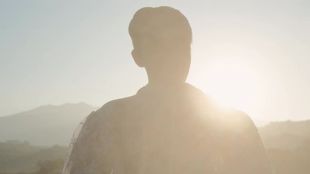 Woman With A Bun Hairstyle Facing The Sunrise