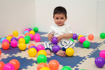 Fototapeta na wymiar happy infant baby playing colorful balls in playpen
