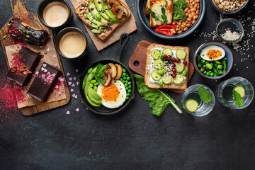 Fototapeta na wymiar Tasty food with avocado toast, vegetables, eggs on dark background. Helthy breakfast concept