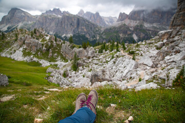 Naklejka na ściany i meble Trekking boots of a hiker while sitting on top of a mountain in Dolomites, Italy