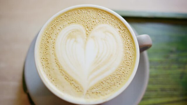 Close vertical view of a coffee foam with painted heart on it