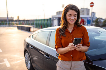 Woman using mobile phone, communication or online application, standing near car on city street or...