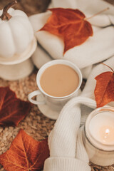 Latte coffee surrounded by fall decorations and white sweater