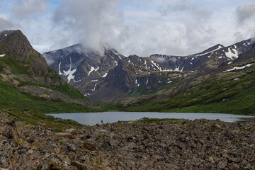Tiny silhouette in expansive landscape of mountains and a lake.