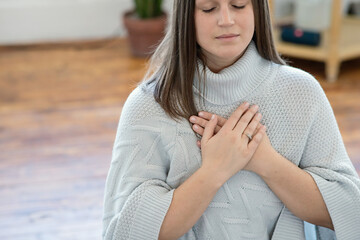 Close up photo of a woman meditating with her hands on heart