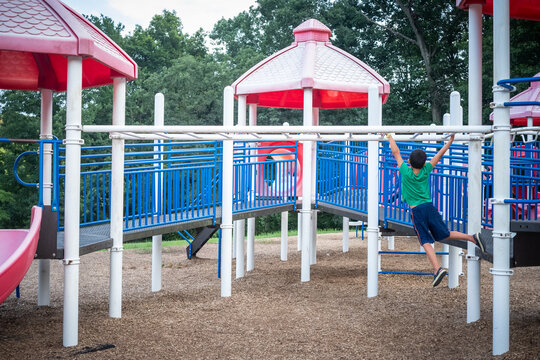 Young boy playing on monkey bars in suburban playground. - Powered by Adobe