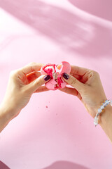 Сlose-up of woman's hand holding macaroon on pink background