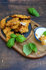 
 Crispy  deep fried   chicken strips and wedges potato. Breaded  with cornflakes chicken  breast fillets  with chilly peppers and fresh   basil on wooden rustic background