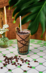 Cacao drink with banana and peanut butter on a table with vase of flowers