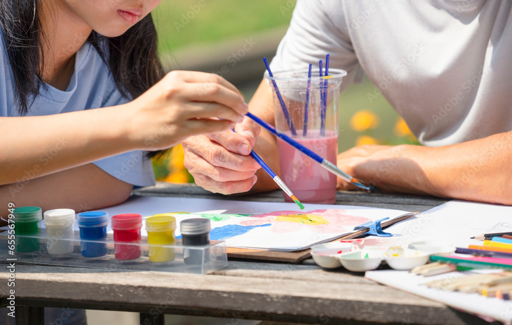 Wall mural teenage girl concentrate on painting with grandfather in the summer garden, concept family lifestyle,activity together,relationship,raising teen, the love of a family