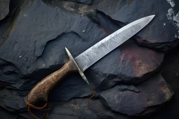 Fototapeten hunting knife lying on a stone, with sharpening dust around © altitudevisual