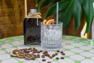 Cold brew coffee in a bottle with transparent glass full of ice on light gray background